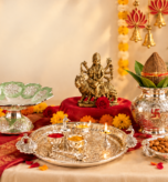 Navratri puja gift collection with a goddess idol, silver thali, kalash, diyas, flowers, and dry fruits