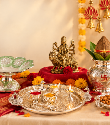 Navratri puja gift collection with a goddess idol, silver thali, kalash, diyas, flowers, and dry fruits