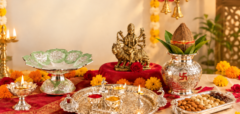 Navratri puja gift collection with a goddess idol, silver thali, kalash, diyas, flowers, and dry fruits